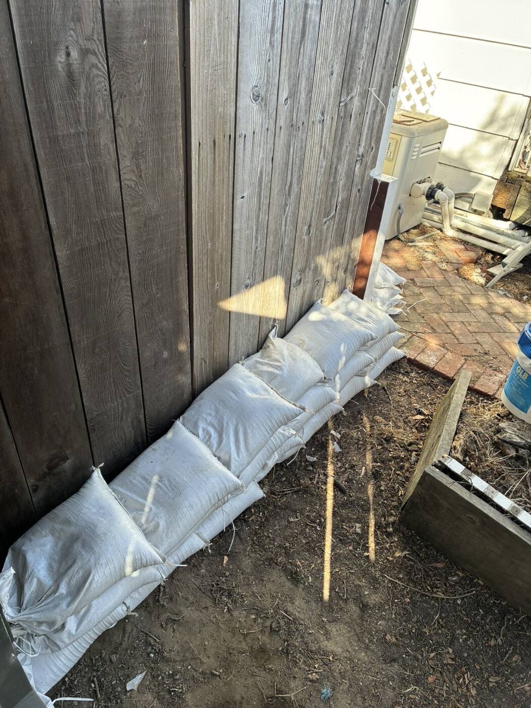 Sandbag run along the bottom of a tall wooden fence