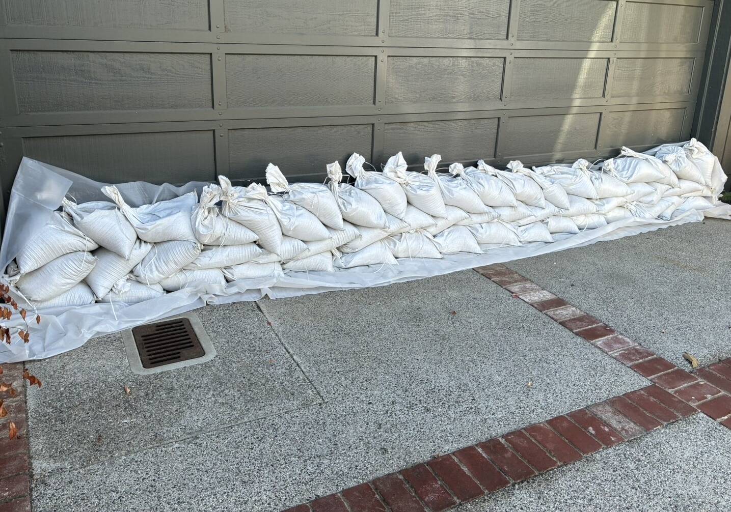 Double row of sandbags on plastic sheeting across a garage door in Larkspur