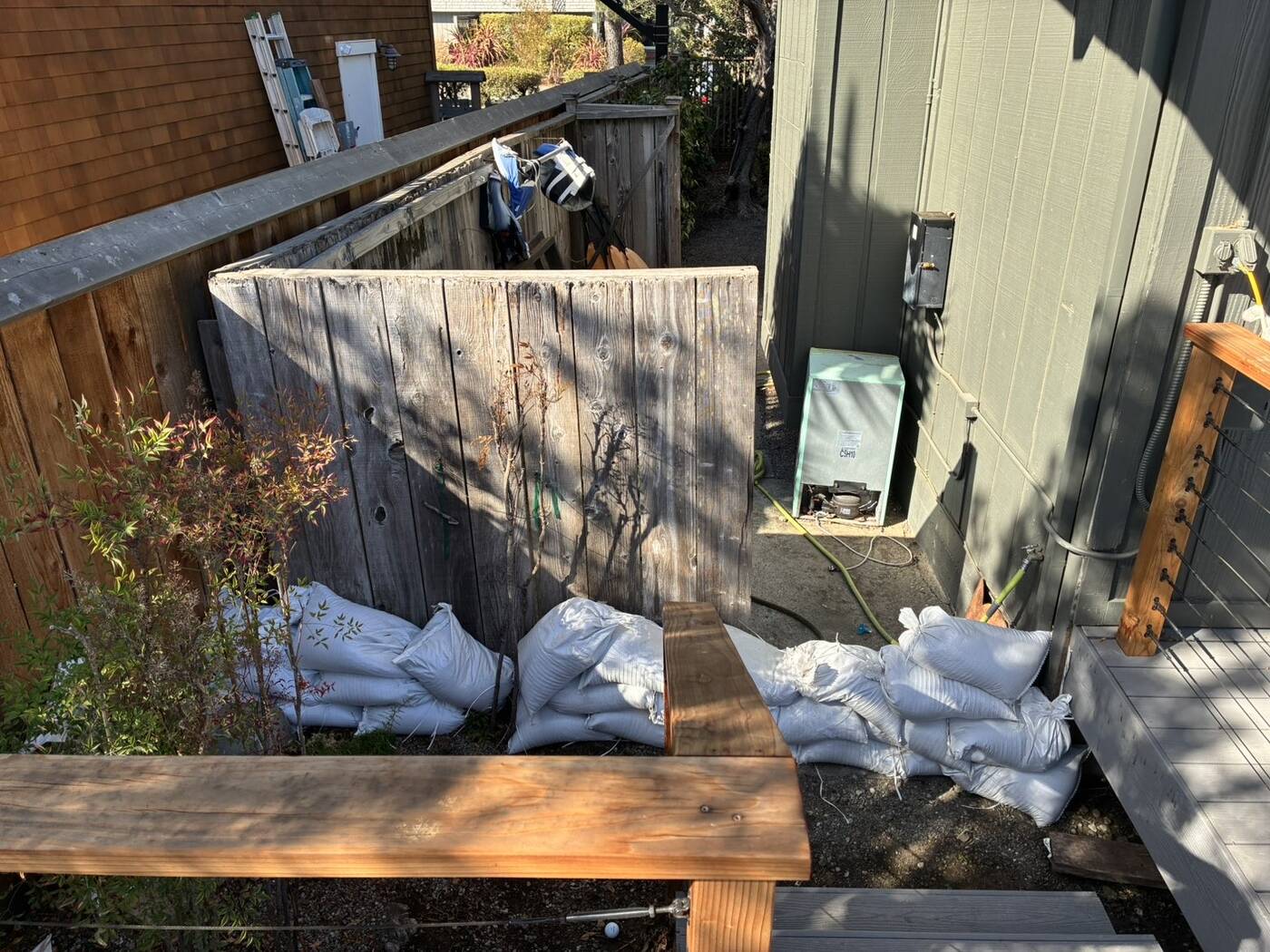 Wide view of sandbags along a yard fence up to the house